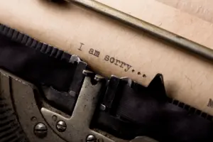 close up of a piece of paper in a typewriter with he words "I am sorry".