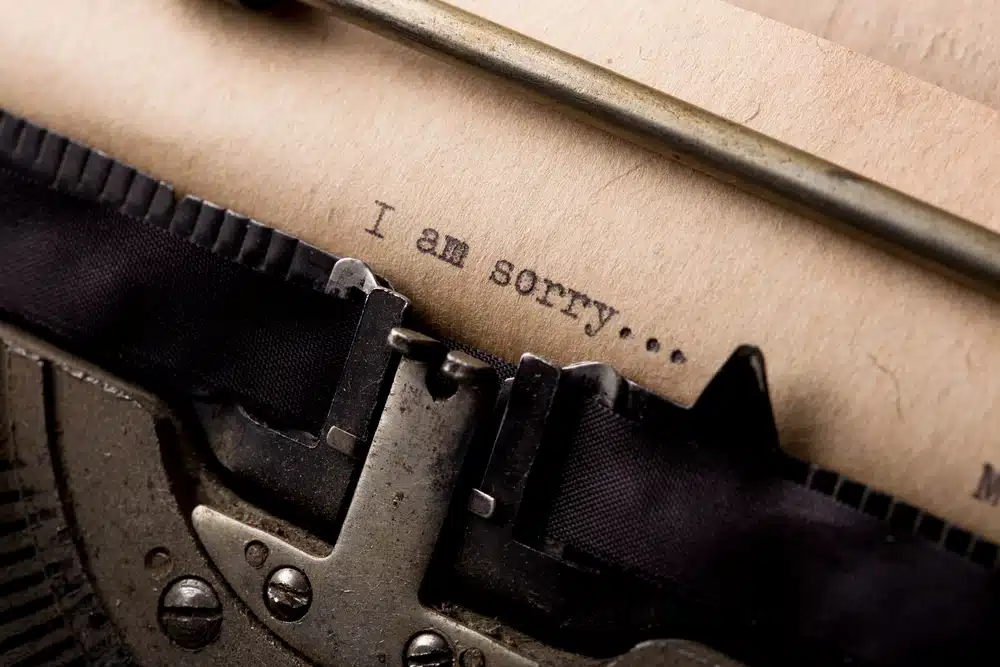 close up of a piece of paper in a typewriter with he words "I am sorry".