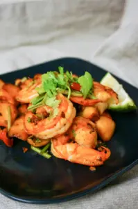 plate of shrimp garnished with cilantro and lime