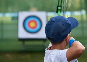 young boy shoots arrows at a target