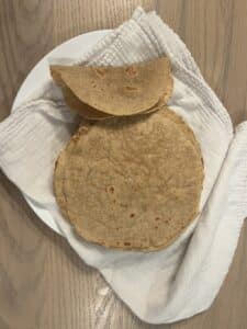 best whole wheat flour tortillas stacked on a plate with one folded