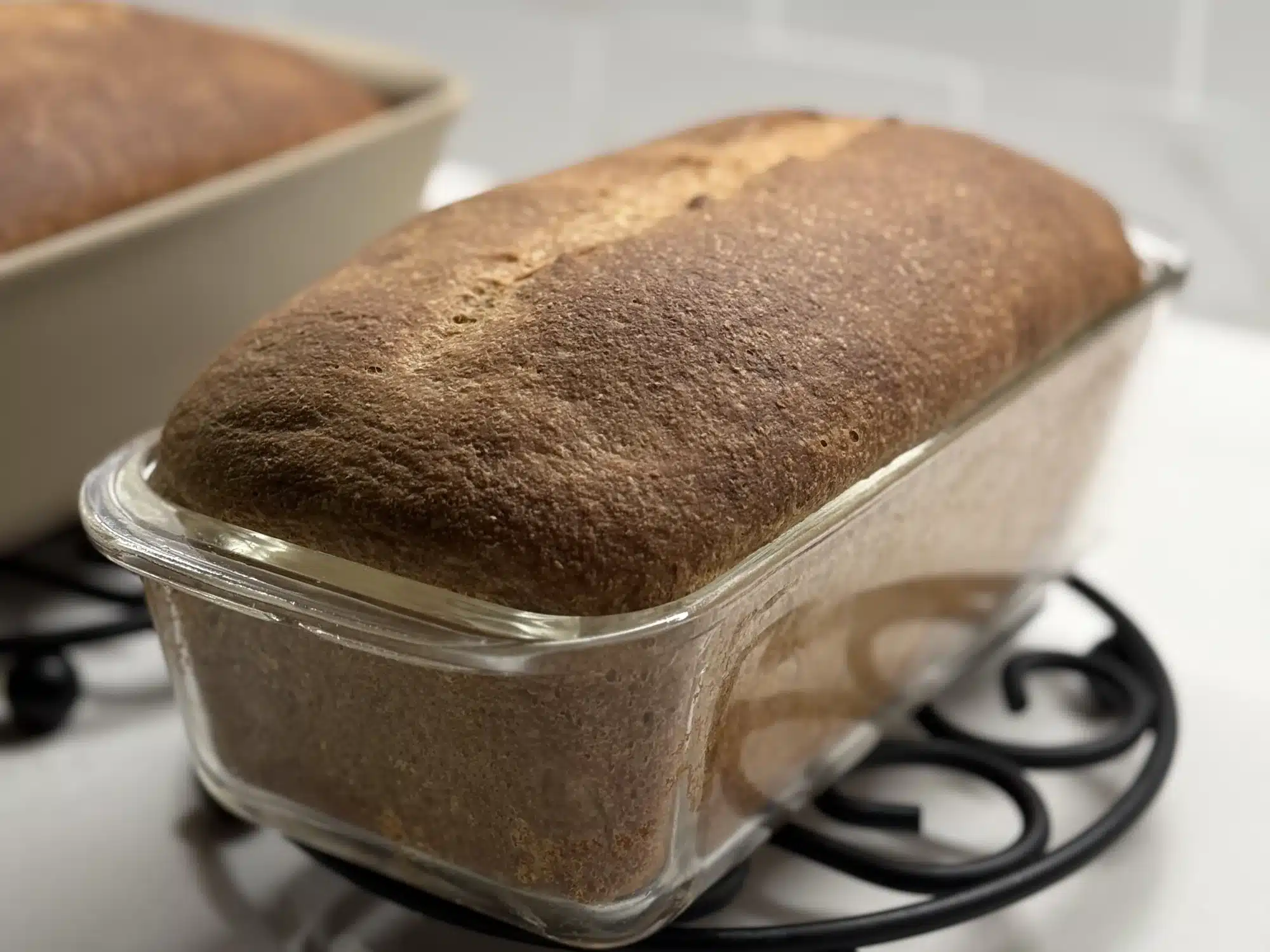 Side angle shot of baked sourdough sandwich bread in glass loaf pan