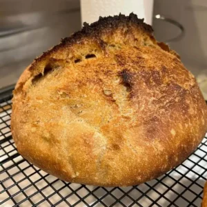 baked sourdough boule with ear on wire rack